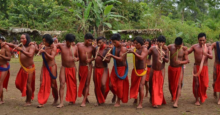 waiãpi, indígenas, 9 homens, homens tocando instrumento de sopro, celebração indígena, massacre, indigenismo, roupas vermelhas